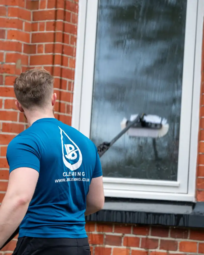 JB Cleaning operative cleaning a window with a water-fed pole