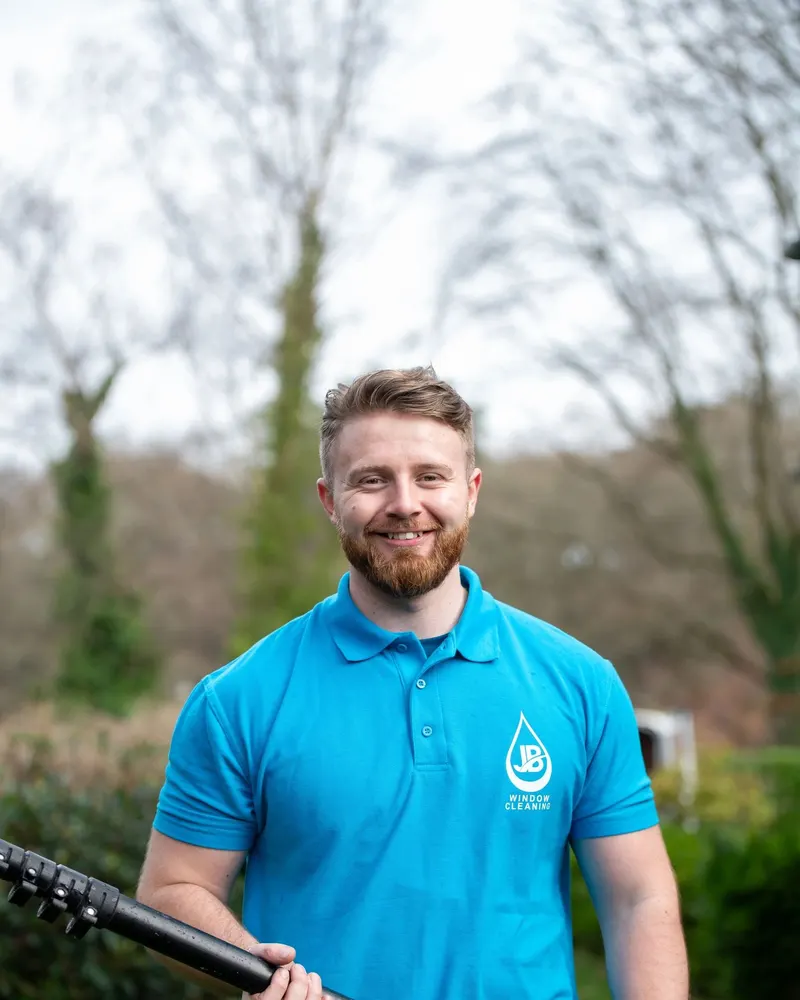 JB Cleaning window cleaner smiling with his water-fed pole